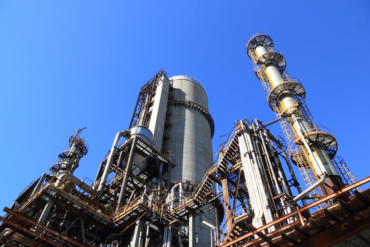 A towering industrial plant under a vivid blue sky, showcasing its intricate architecture and industrial prowess.